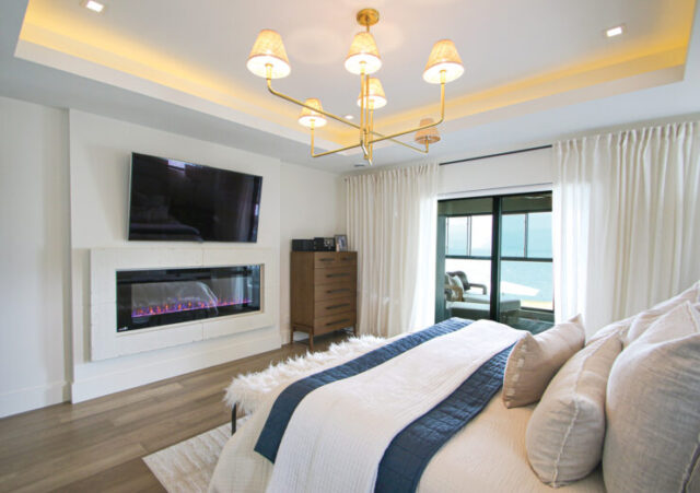 The primary bedroom follows a light, neutral color palette and features a balcony, allowing the couple to enjoy the beautiful view even more.